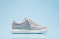 create side view of a light gray partial suede sneaker with light sky blue back ground